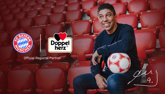 A smiling man sitting in red stadium seats holds a soccer ball. Logos of FC Bayern München and Doppelherz are displayed, highlighting their partnership. The background features empty seats, emphasizing the sporting venue.